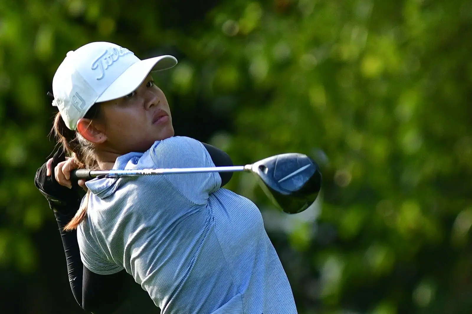 A player follows the flight of her tee shot